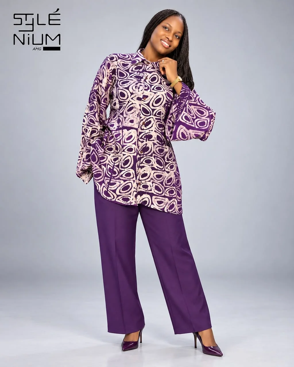 Femme portant une chemise ample à imprimé violet et rose pâle avec un pantalon droit violet, création AMG STYLENIUM
