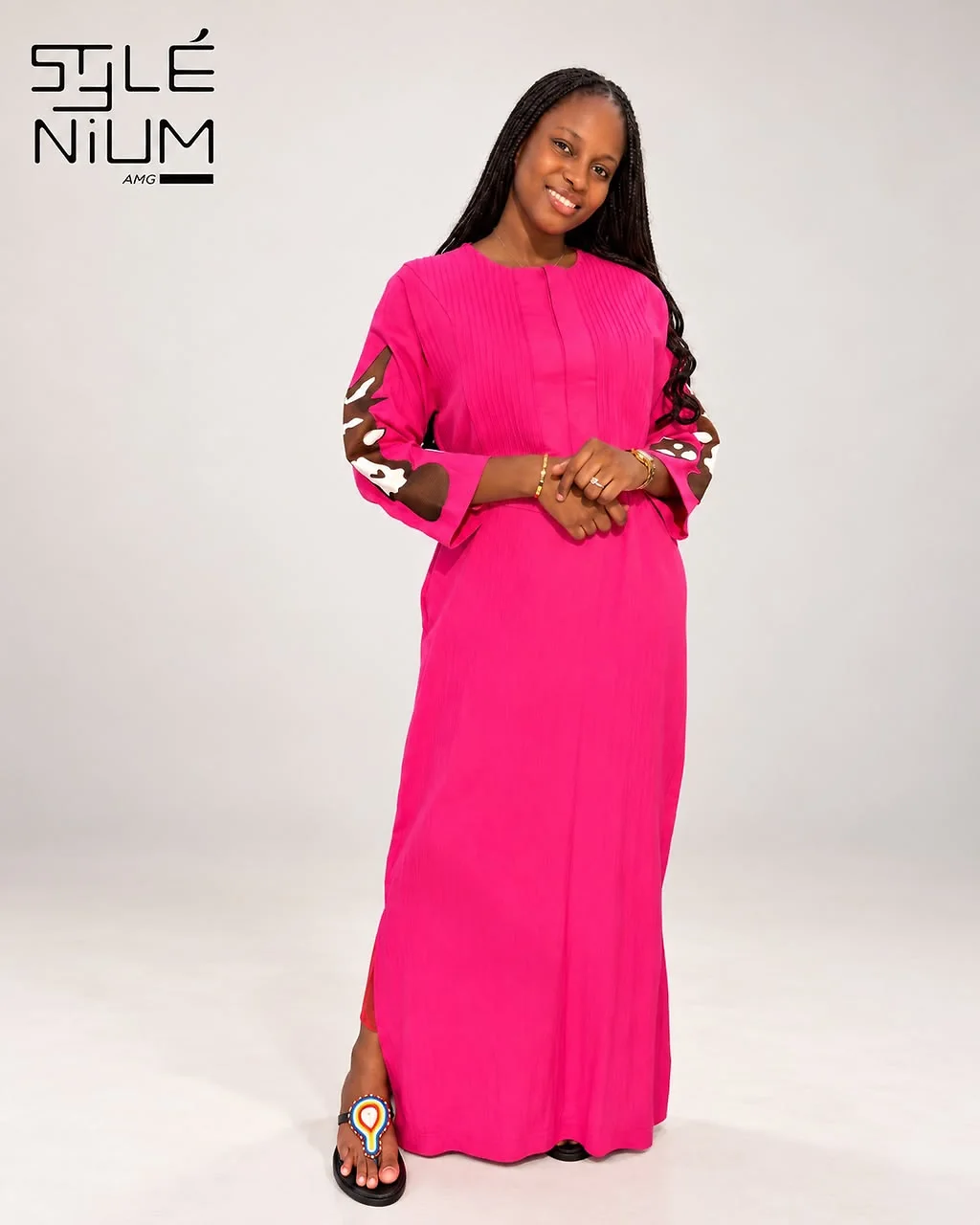 Femme portant une robe longue fuchsia avec nervures au buste et appliqués marron et blanc sur les manches, création AMG STYLENIUM