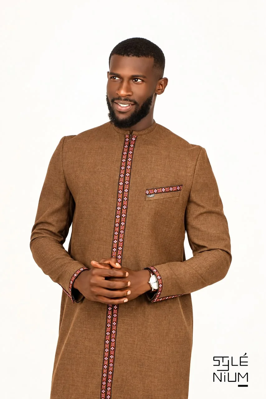 Homme portant une tunique longue marron ornée de galons bordeaux à motifs le long de l'ouverture, des poignets et de la poche, création AMG STYLENIUM