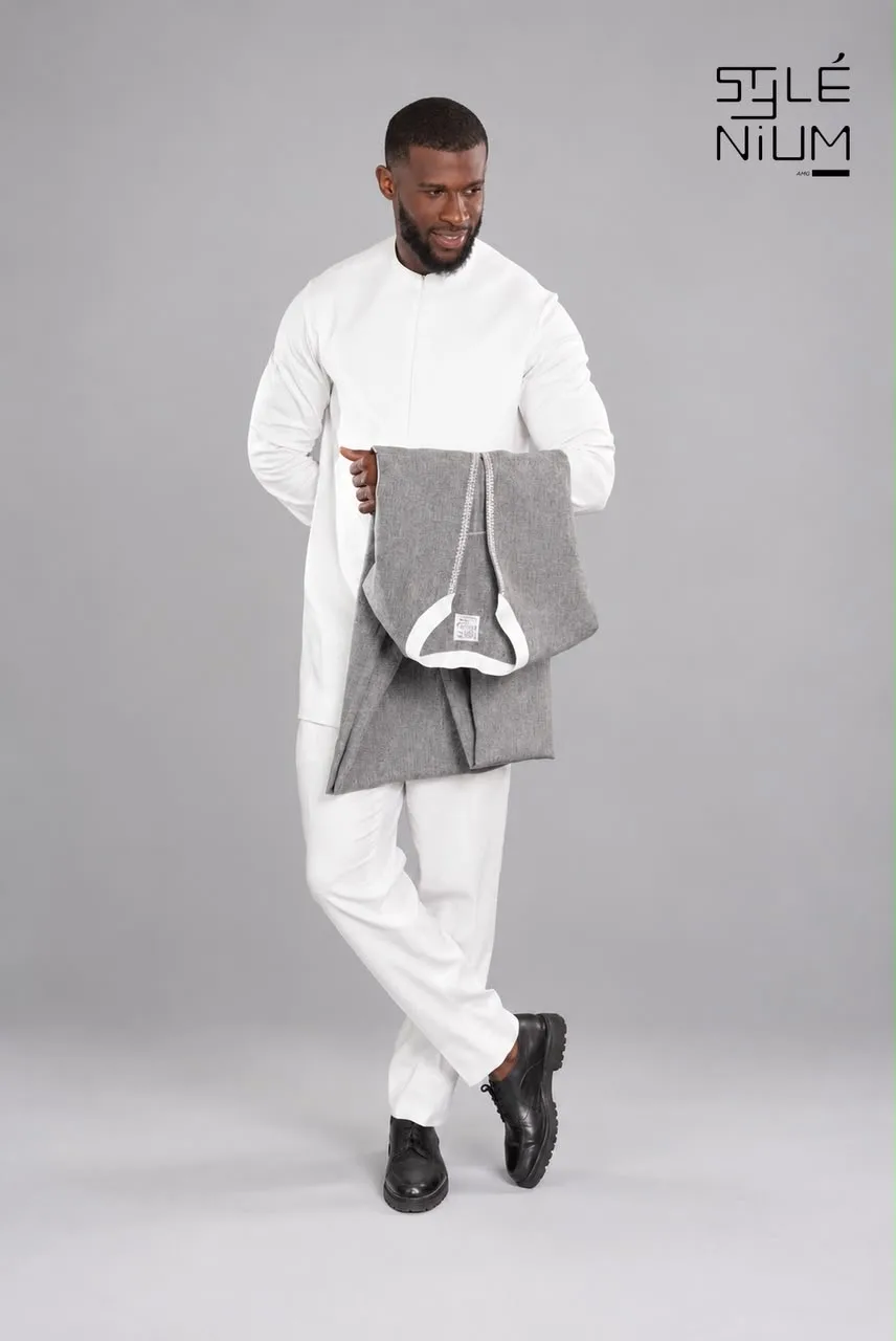 Homme portant un ensemble tunique et pantalon blanc, tenant une pièce grise pliée, création AMG STYLENIUM