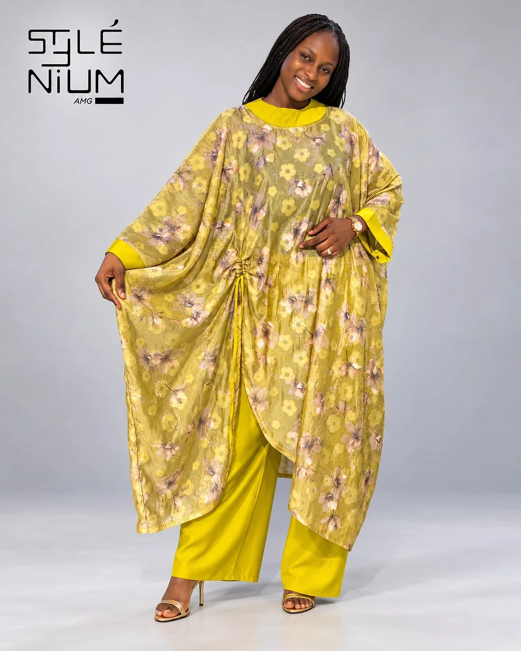 Femme portant une tunique ample jaune à fleurs, froncée par un cordon sur le côté, avec un pantalon large jaune, création AMG STYLENIUM