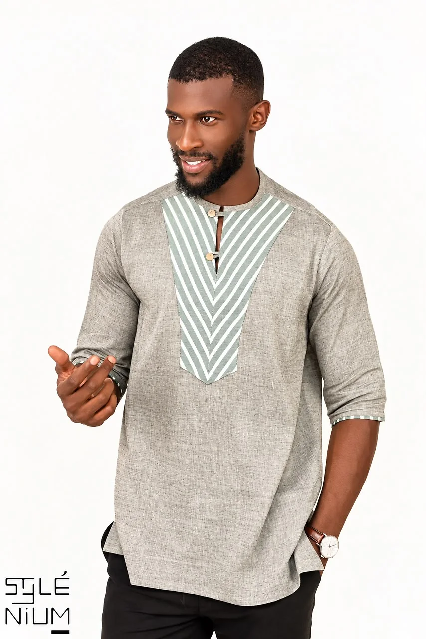 Homme portant une tunique grise à manches trois-quarts avec un plastron en V à chevrons vert et blanc et deux boutons, création AMG STYLENIUM